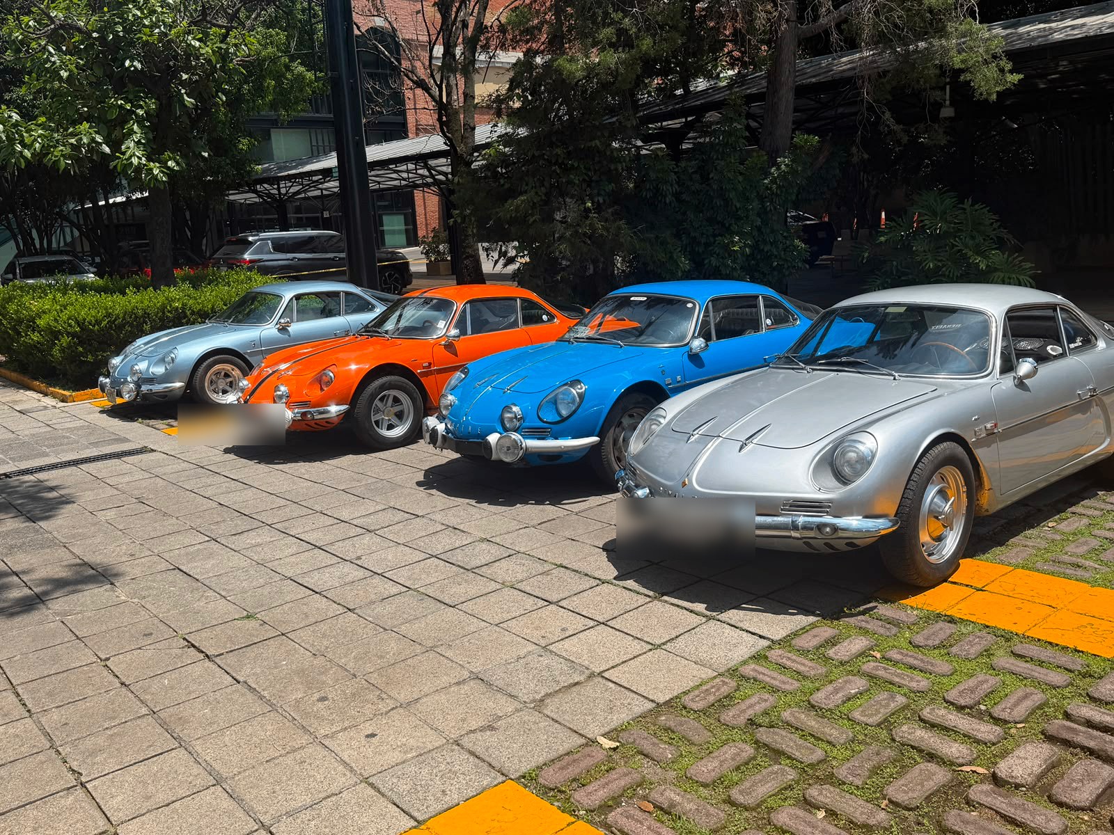 Fila de Alpine clásicos plata, naranja, azul y plata durante el desayuno del 12 de julio de 2026, con matrículas difuminadas