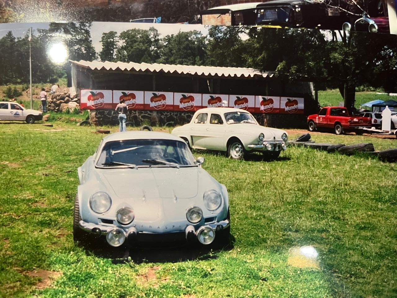 Alpine A110 azul claro y Renault Dauphine blanco sobre el pasto