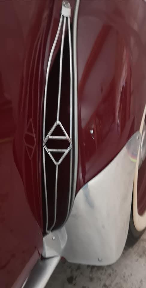 Detalle de la parrilla y emblema de un Renault 4CV guinda