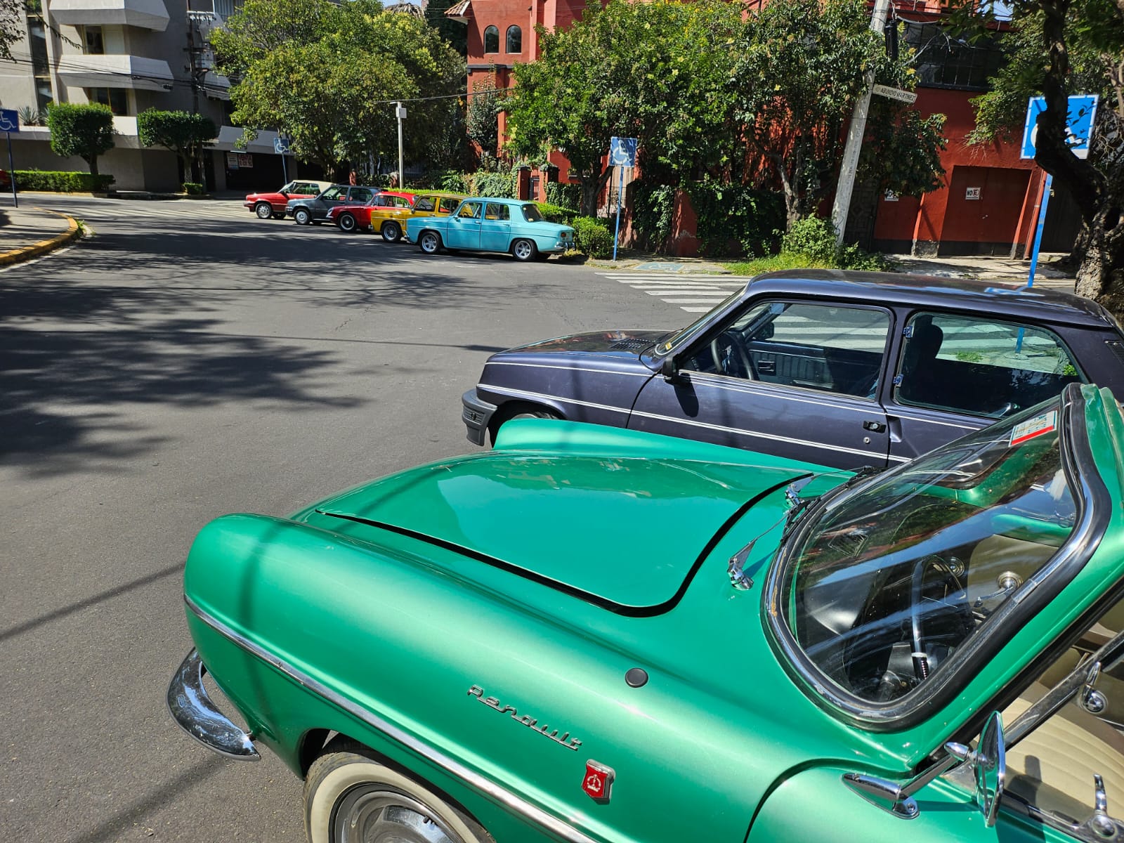 Renault Floride verde con Renault 5 al fondo y fila de clásicos en la calle