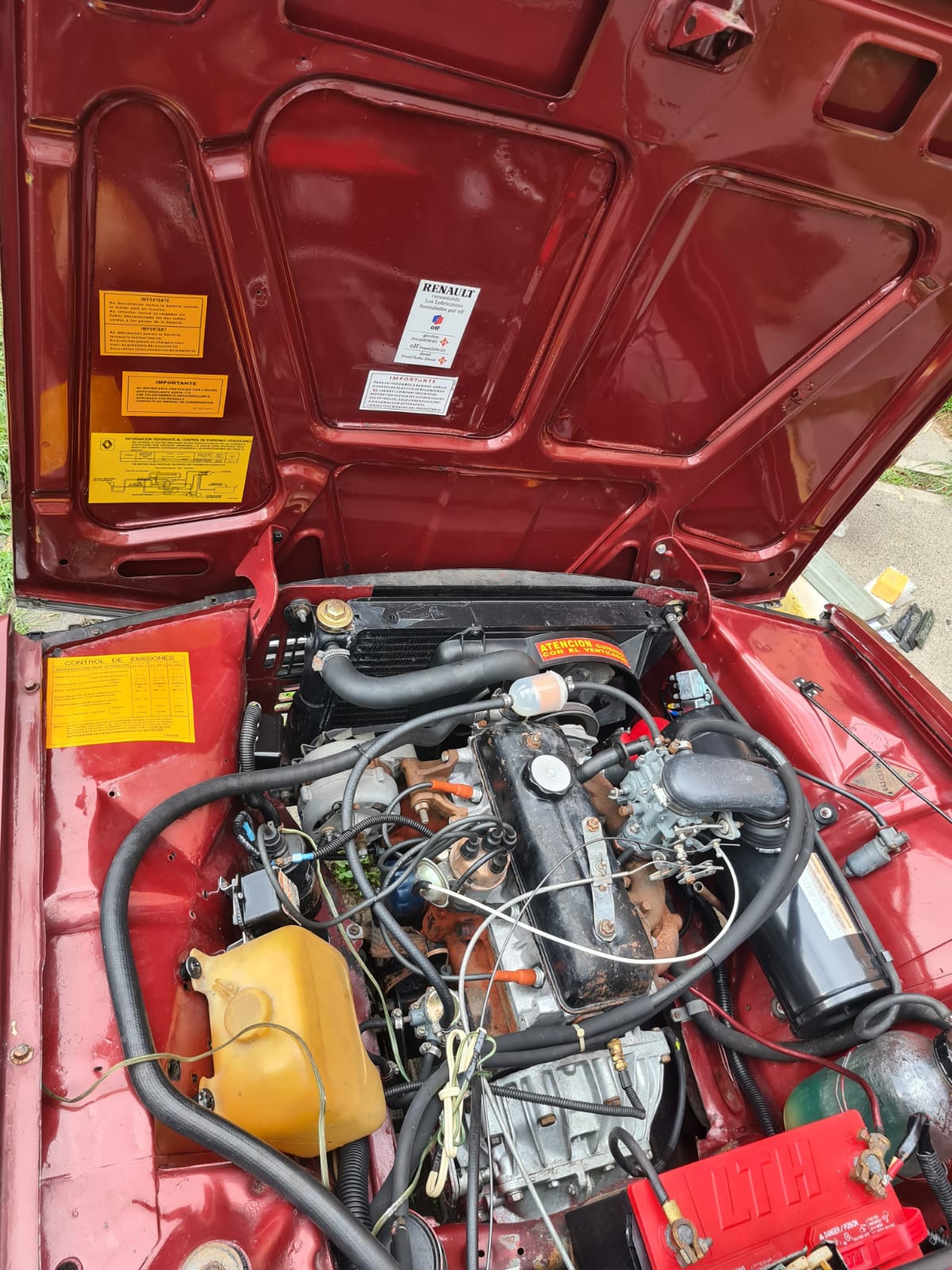 Motor Renault visto con el cofre rojo abierto y calcomanías originales