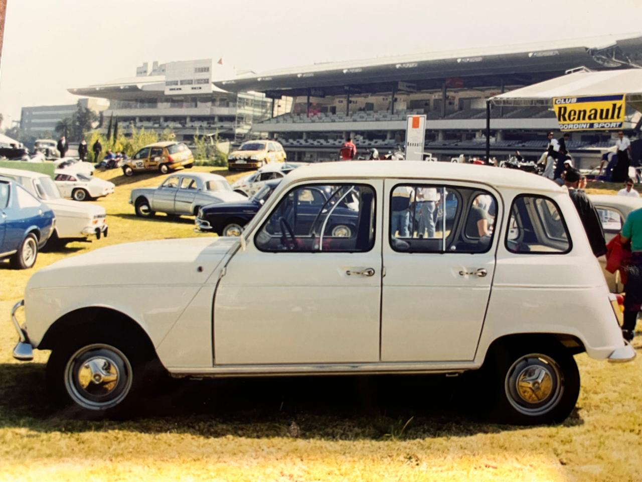 Renault 4L blanco de perfil con clásicos Renault y stand del Club Renault Gordini Sport al fondo en el Autódromo Hermanos Rodríguez