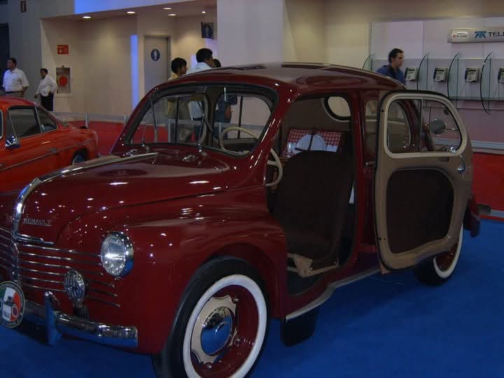 Renault 4CV guinda con la puerta suicida abierta en exhibición